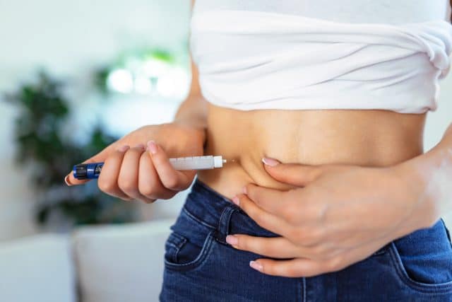 Kvinne setter insulin i magen, en mage full av stikkskader